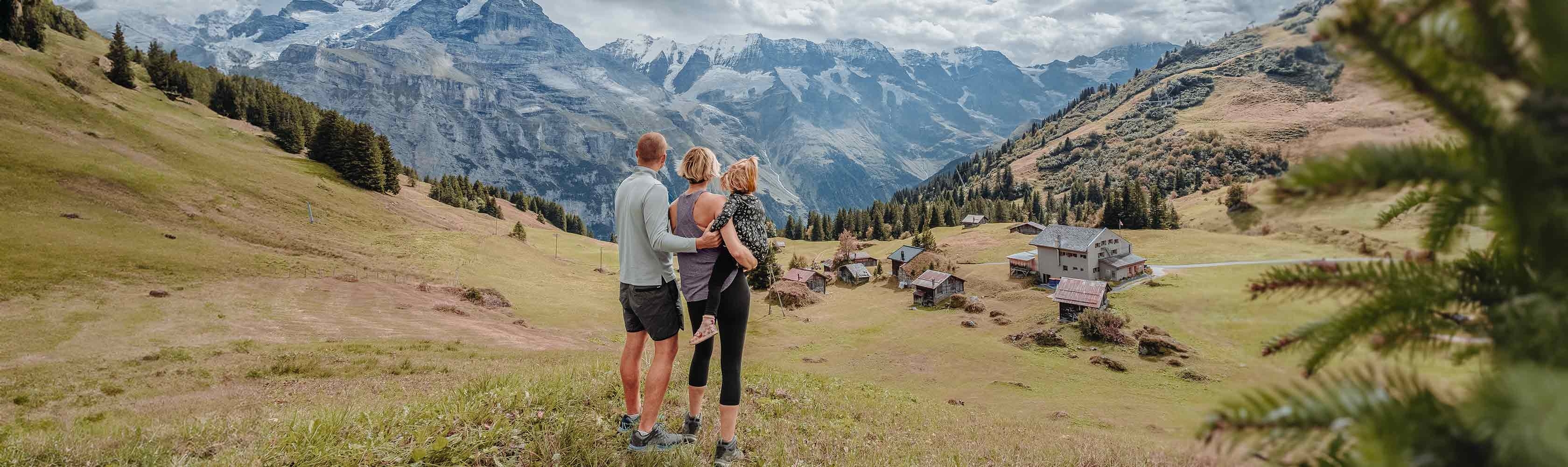Neu in der Schweiz - Familie mit zwei Kindern blickt beim Wandern auf einen See.