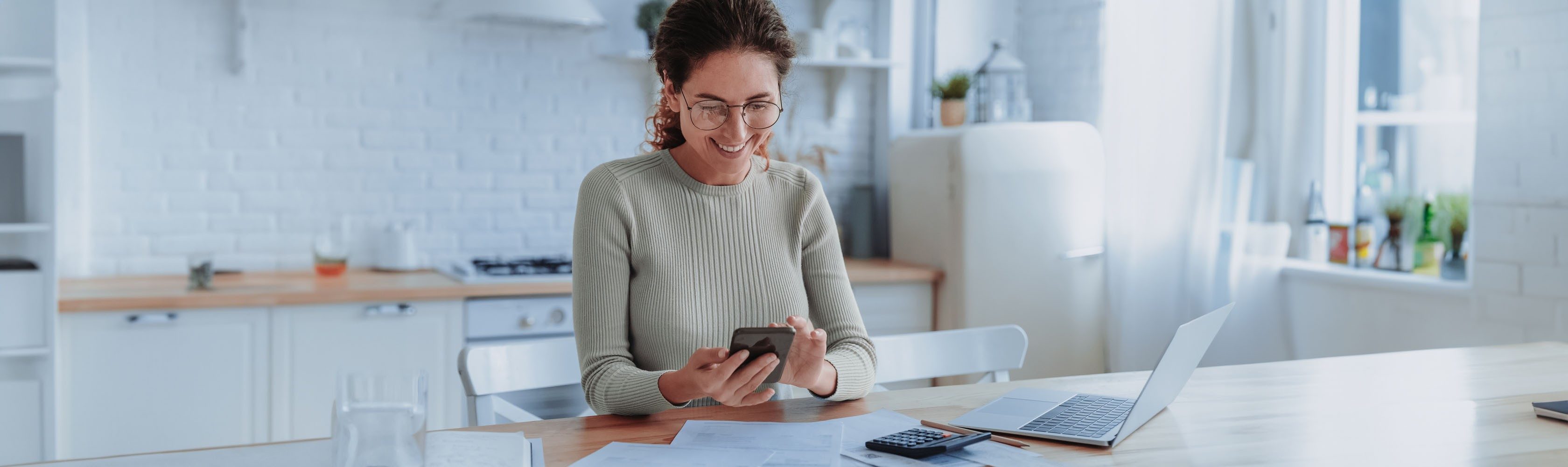 E-Bill - Eine Frau sitz an einem Tisch und bezahlt ihre Rechnungen mit eBill.