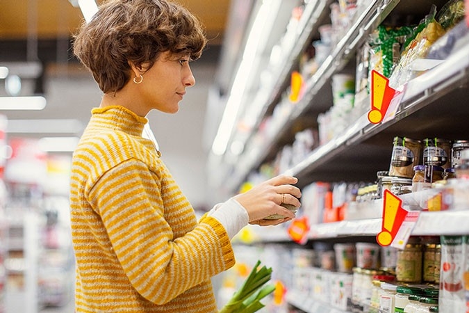 Eine Frau steht im Supermarkt vor einem grossen Regal. 
