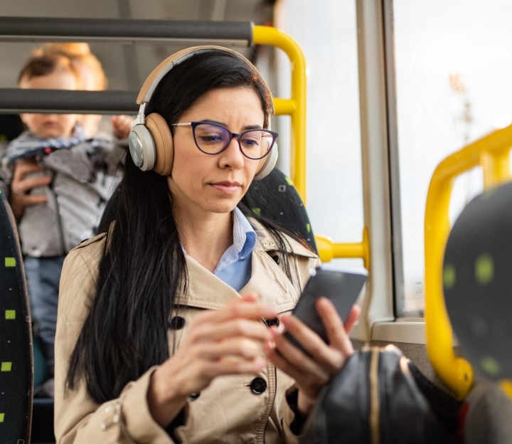 Ein Frau sitzt im Bus und holt sich via Mobile-App Empfehlungen für eine gesunde Ernährung.