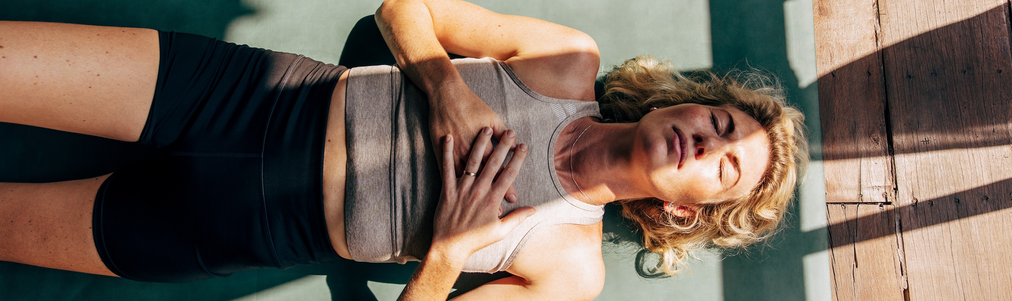 Eine Frau liegt auf der Yogamatte und meditiert.