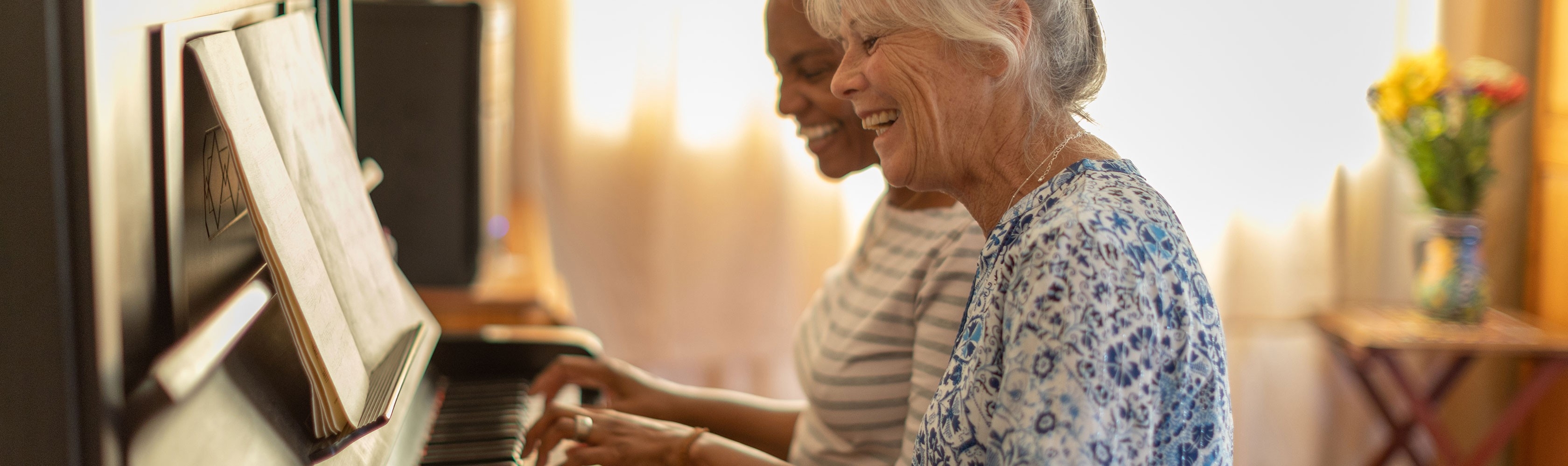 Zwei Frauen üben am Klavier und haben Freude daran.