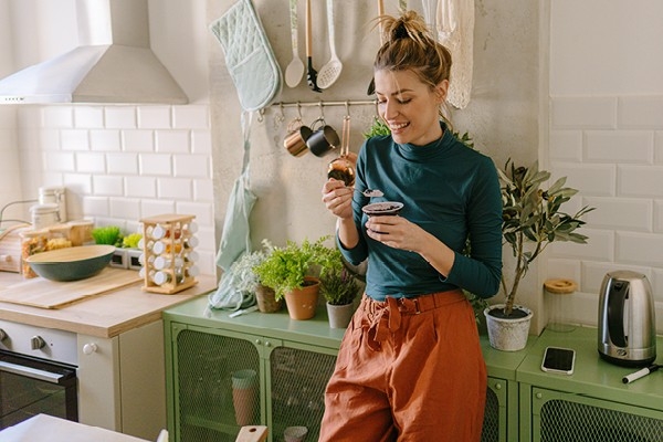 eine junge Frau geniesst einen Snack zwischendurch in ihrer Küche