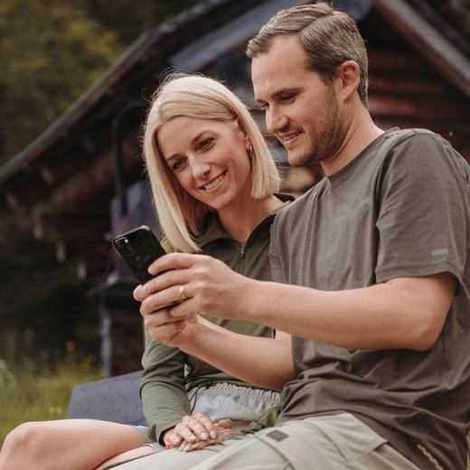 MyConcordia - Ein Mann hält ein Smartphone in den Händen, auf welches er zusammen mit einer Frau schaut.