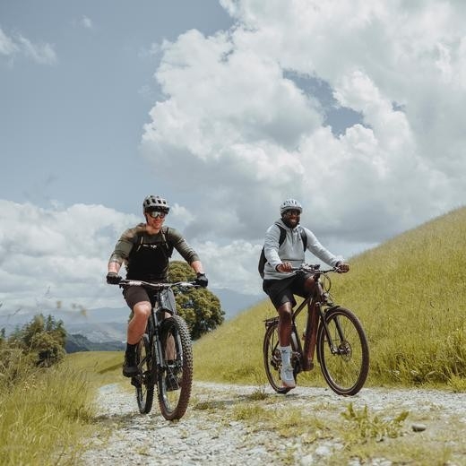 Concordia-Active - 2 Männer fahren mit ihren Mountainbikes bei bestem Wetter über einen Kiesweg.