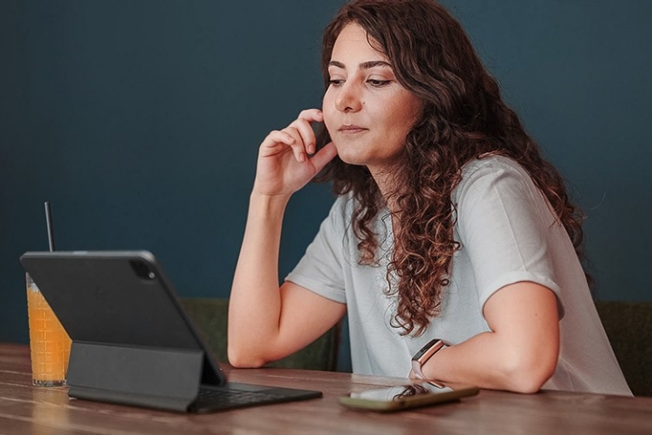 Eine Frau sitzt nachdenklich vor ihrem Tablet