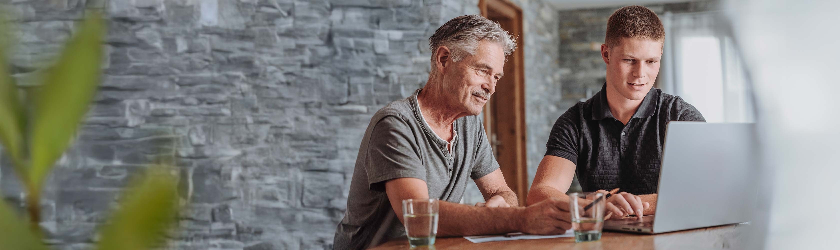 Kundenzufriedenheit – Senior und junger Mann besprechen etwas am Laptop.