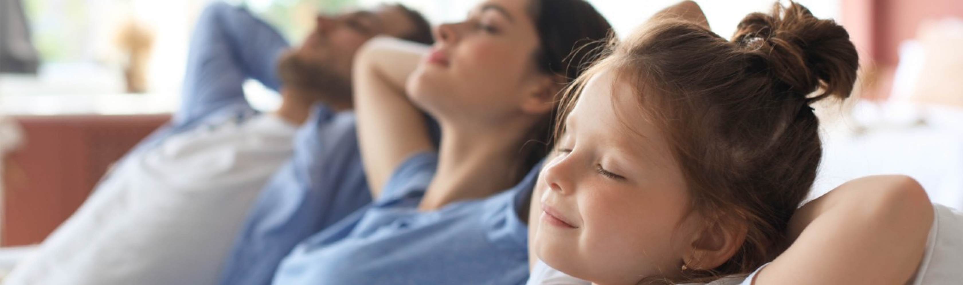 Gesünder leben: Vater, Mutter und Tochter entspannen gemeinsam auf dem Sofa.