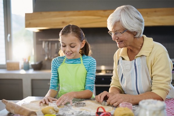 Ein Mädchen und ihr Grosi backen gemeinsam Guetzli. Traditionen, Rezepte und Hausmittel werden über Generationen weitergegeben.