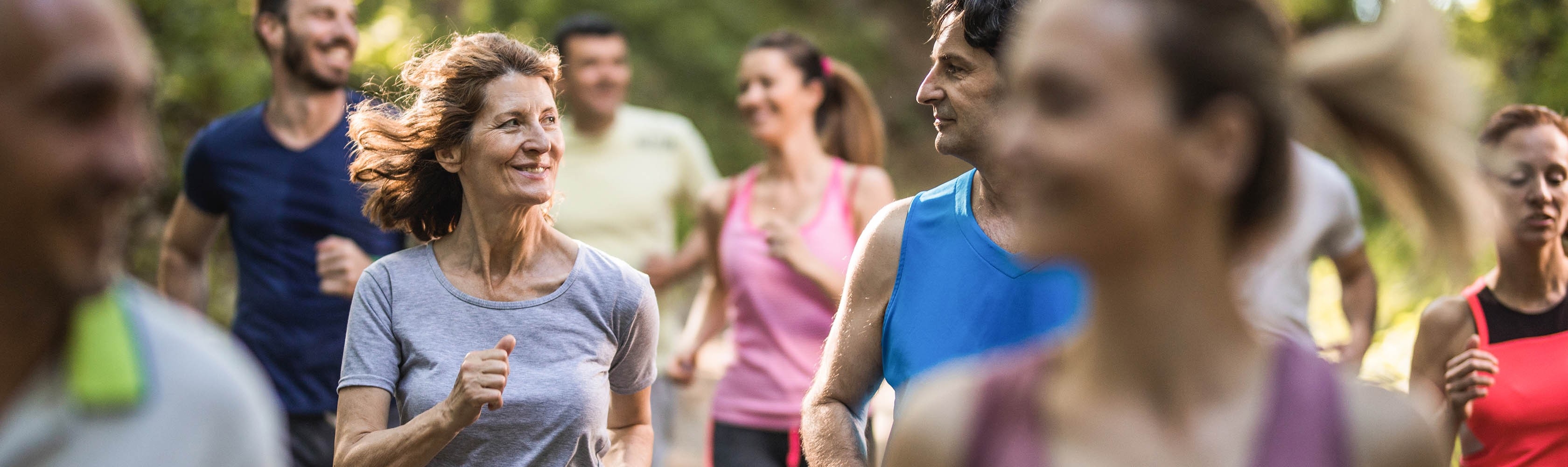 Eine Gruppe von verschiedenen Personen joggen gemeinsam im Wald.