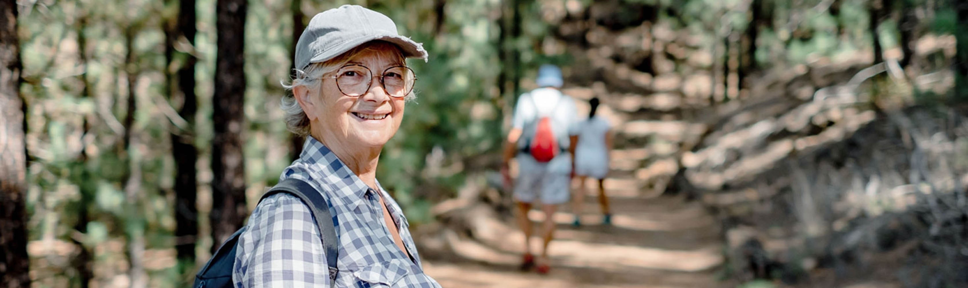 Eine ältere Frau geniesst eine Wanderung mit Freunden im Wald