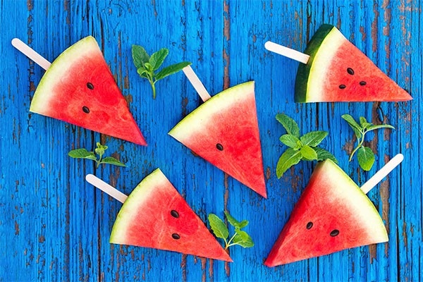 Zu sehen sind Stücke von Wassermelone auf je einem Eisstiel. Perfekt für den Sommer: Rezepte für selbstgemachtes Eis.
