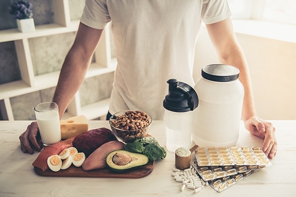 Sport und Ernährung: eine Person steht vor einer Auswahl an gesunden Lebensmittel und Nahrungsergänzungsmittel