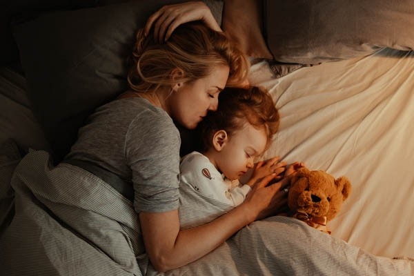 Mutter und Kind schlafen gemeinsam ein.