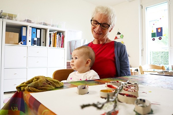 In der Tagesstätte TANDEM dekorieren und spielen Jung und Alt Hand in Hand. Eine Seniorin bastelt zusammen mit der jüngsten Generation an der neuen Dekoration