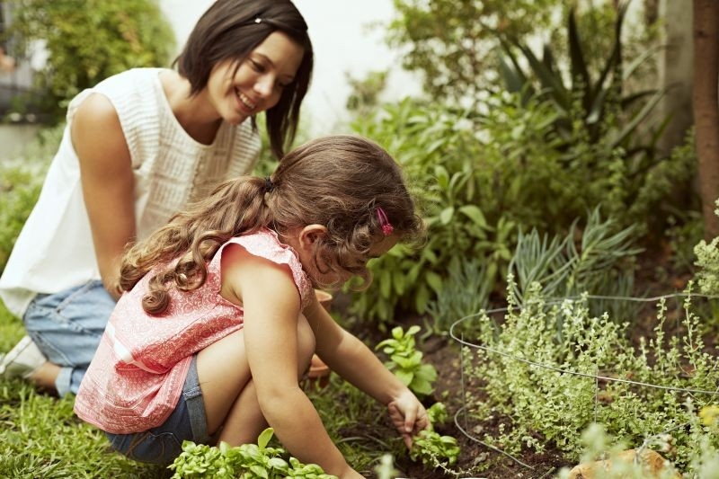 Mutter und Kind im Garten. Kinder ahmen ihre Eltern nach und lernen so dazu.