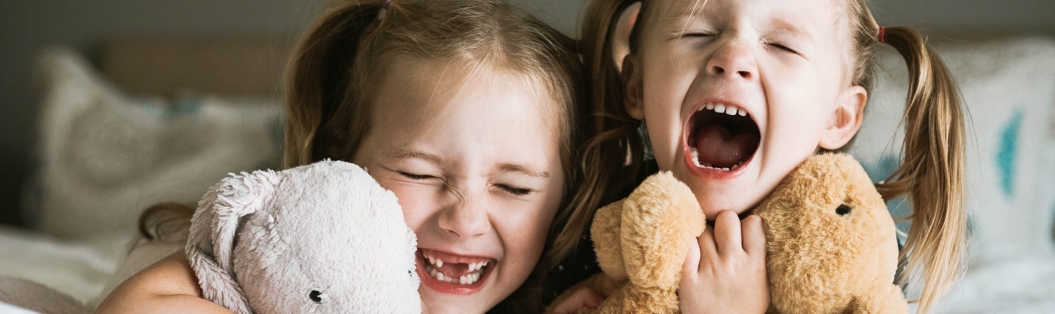 Zwei Mädchen lachen. Eine Zahnversicherung lohnt sich, besonders für Kinder.